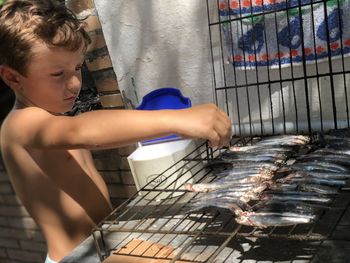 Cute boy pouring salt on fishes