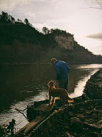 Man with dog on lake against sky