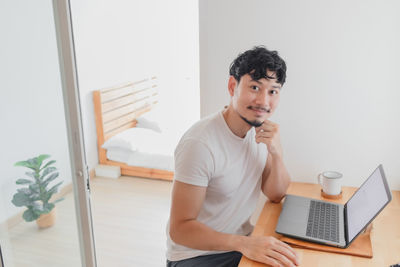 Young man using mobile phone while sitting on table