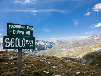 Information sign on snowcapped mountains against sky