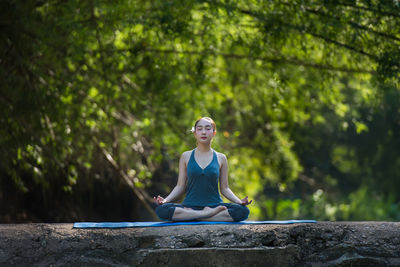 Full length of woman practicing yoga against trees