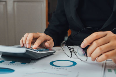 Midsection of businesswoman using calculator at office