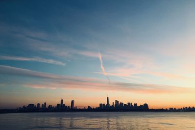 Sea and buildings against sky during sunset