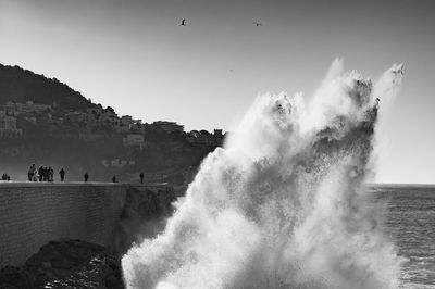 Panoramic shot of sea waves splashing against clear sky