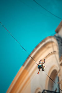 Low angle view of rope hanging on building against blue sky