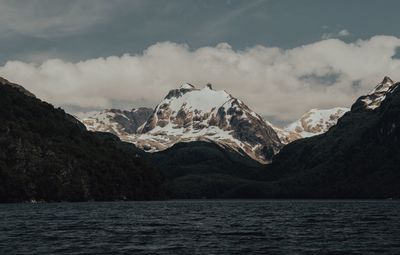 Scenic view of sea by mountains against sky