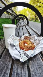 Food with foil on wooden bench at park