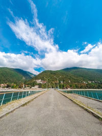 Road leading towards mountains against blue sky