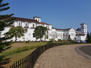 Footpath by buildings against clear blue sky