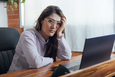 Portrait of young woman using laptop at table