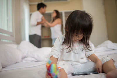 Girl watching video in mobile phone while parents arguing at home