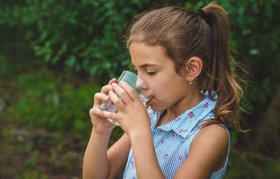 Side view of girl drinking water from glass