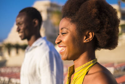 Profile view of young woman smiling while standing outdoors