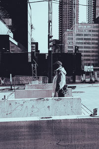Man sitting on street against buildings in city