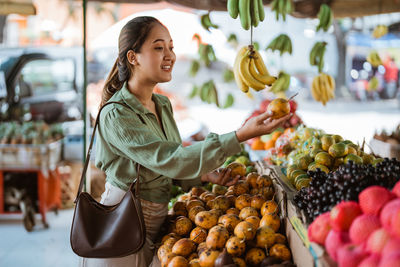 Portrait of woman holding fruits for sale