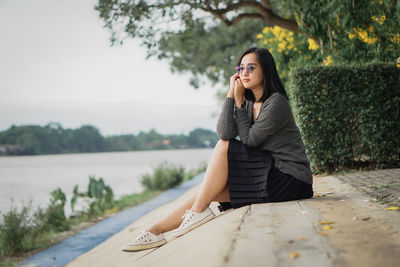 Portrait of young woman sitting on retaining wall