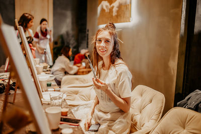 Young woman holding food while sitting on table