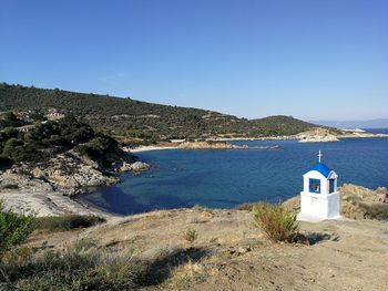 Scenic view of sea by building against clear blue sky