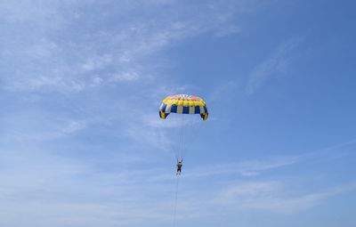 Low angle view of person paragliding against sky