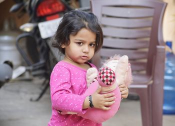 Cute girl holding pink toy while standing outdoors