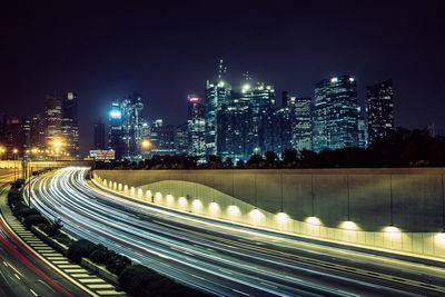 Light trails on road in city against sky at night