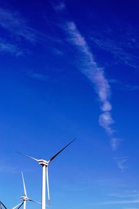 Low angle view of wind turbines against blue sky