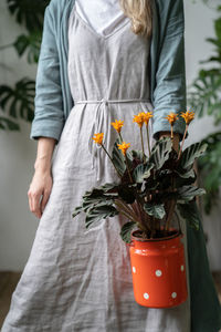 Beautiful woman standing by potted plant