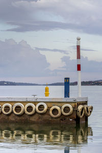 Tires on pier over sea at sunset