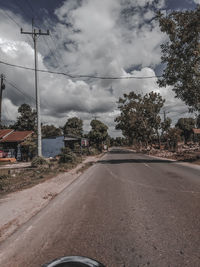 Road by trees against sky