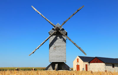 Traditional windmill on field against clear blue sky