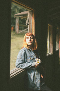 Portrait of young woman standing against wall