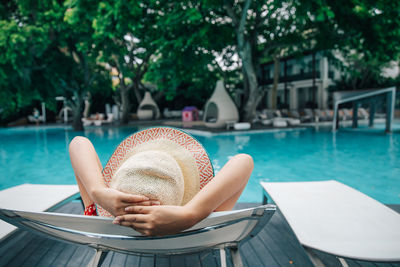 Woman relaxing on chair at swimming pool