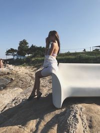 Side view of woman sitting on sofa at beach