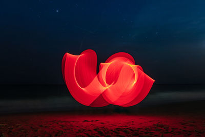 Red umbrella on beach against sky at night
