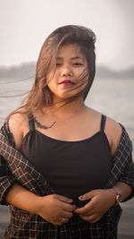 Young adult woman standing by river side.