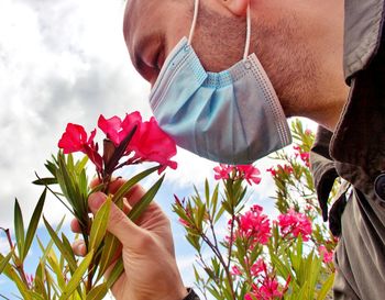 Man smelling a flower with a surgical mask