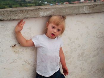 Portrait of cute girl standing against wall