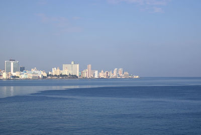 Sea by buildings against blue sky