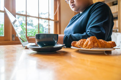 Midsection of woman using laptop at cafe