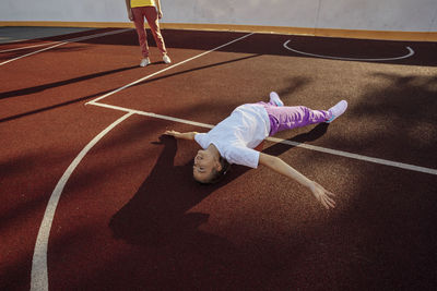 Laid-back laughter, unwinding with children on the basketball court surface with mother