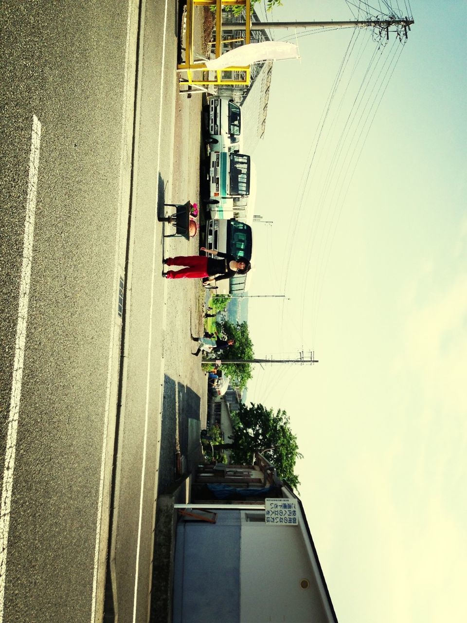 transportation, power line, mode of transport, building exterior, built structure, architecture, street, sky, land vehicle, electricity pylon, tree, road, car, city, cable, road sign, street light, day, outdoors, low angle view