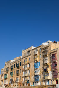 Low angle view of buildings against clear blue sky