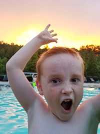 Close-up portrait of happy boy against sky during sunset