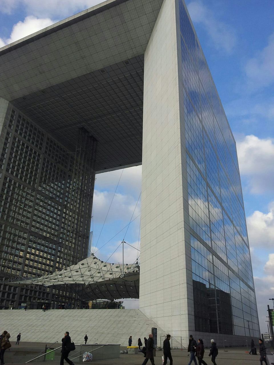 architecture, built structure, building exterior, city, sky, cloud - sky, modern, city life, famous place, office building, capital cities, cloud, skyscraper, tall - high, tower, men, large group of people, travel destinations, low angle view