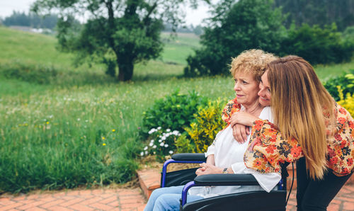 Cheerful daughter visiting ill mother in nursing home at park