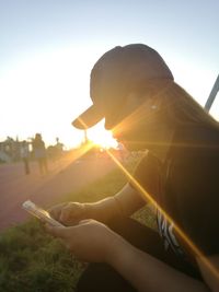 Midsection of woman using mobile phone against sky