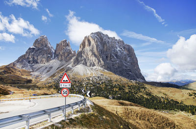 Road sign by mountains against sky