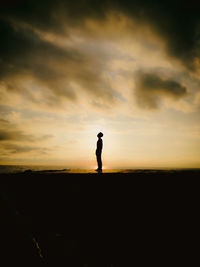 Silhouette man standing on beach against sky during sunset