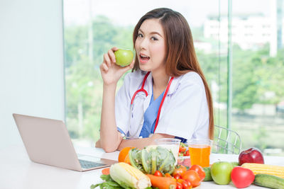 Young woman using mobile phone while sitting on table