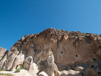 Low angle view of rocks against clear blue sky